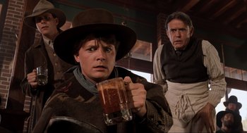 Movie still from “Back to the Future Part III” (1990), directed by Robert Zemeckis – A man holding a mug in front of another man; Medium shot, Low angle