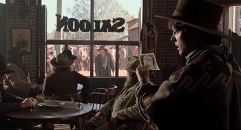 Movie still from “Back to the Future Part III” (1990), directed by Robert Zemeckis – A man sitting at a table in front of a window; Wide shot, Over the shoulder angle