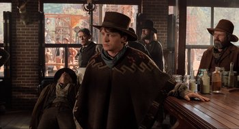 Movie still from “Back to the Future Part III” (1990), directed by Robert Zemeckis – A man wearing a hat and a poncho standing next to other men; Medium shot, Over the shoulder angle