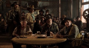 Movie still from “Back to the Future Part III” (1990), directed by Robert Zemeckis – A group of men sitting at a table with drinks; Wide shot, Low angle