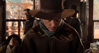 Movie still from “Back to the Future Part III” (1990), directed by Robert Zemeckis – A man wearing a cowboy hat and a brown coat; Medium shot, Over the shoulder angle