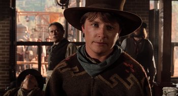 Movie still from “Back to the Future Part III” (1990), directed by Robert Zemeckis – A man wearing a cowboy hat and a sweater; Close Up shot, Over the shoulder angle