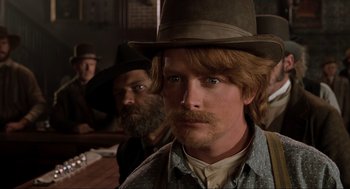 Movie still from “Back to the Future Part III” (1990), directed by Robert Zemeckis – A man with a beard and a hat is looking into the camera; Close Up shot, Low angle