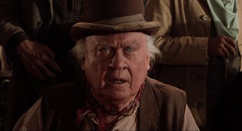 Movie still from “Back to the Future Part III” (1990), directed by Robert Zemeckis – An old man wearing a top hat and a scarf; Close Up shot, Over the shoulder angle