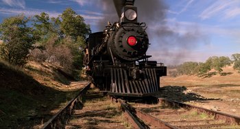 Movie still from “Back to the Future Part III” (1990), directed by Robert Zemeckis – An old steam engine train traveling down the tracks; Extreme Wide shot, Low angle
