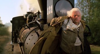 Movie still from “Back to the Future Part III” (1990), directed by Robert Zemeckis – An older man leaning against a train engine; Medium shot, Low angle