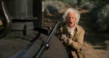 Movie still from “Back to the Future Part III” (1990), directed by Robert Zemeckis – An old man with white hair is climbing a train; Medium shot, Low angle