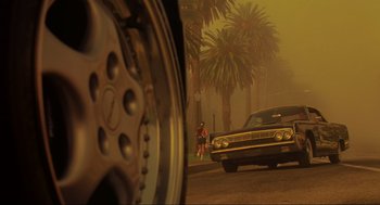 Movie still from “Bad Boys” (1995), directed by Michael Bay – A man walking down a street past a palm tree lined street; Wide shot, Low angle