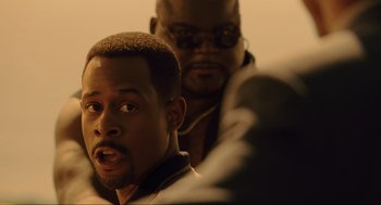 Movie still from “Bad Boys” (1995), directed by Michael Bay – A man with his mouth wide open looking at the camera; Close Up shot, Over the shoulder angle