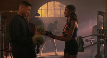 Movie still from “Bad Boys” (1995), directed by Michael Bay – A man and a woman are boxing in a gym; Medium shot, Over the shoulder angle