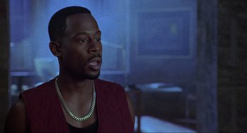 Movie still from “Bad Boys” (1995), directed by Michael Bay – A man in a red vest is looking at the camera; Close Up shot, Over the shoulder angle