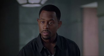 Movie still from “Bad Boys” (1995), directed by Michael Bay – A person wearing a black shirt; Close Up shot, Over the shoulder angle