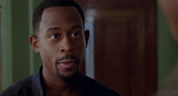 Movie still from “Bad Boys” (1995), directed by Michael Bay – A person wearing a black shirt; Close Up shot, Over the shoulder angle