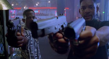 Movie still from “Bad Boys” (1995), directed by Michael Bay – Two men are holding guns in front of a crowd; Close Up shot, Low angle
