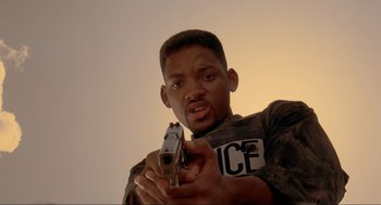 Movie still from “Bad Boys” (1995), directed by Michael Bay – A man holding a gun in front of a camera; Close Up shot, Low angle