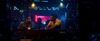 Movie still from “Bad Boys for Life” (2020), directed by Adil El Arbi – A man sitting at a table in front of two other men; Medium shot, Over the shoulder angle