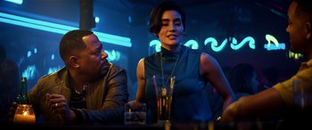 Movie still from “Bad Boys for Life” (2020), directed by Adil El Arbi – A woman sitting at a table with a glass of water; Medium shot, Over the shoulder angle