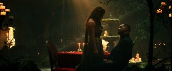 Movie still from “Bad Boys for Life” (2020), directed by Adil El Arbi – A man and a woman sitting on a red couch in front of a staircase; Wide shot, Over the shoulder angle