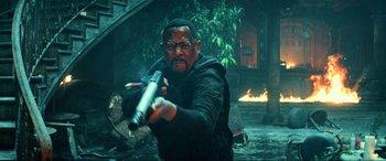 Movie still from “Bad Boys for Life” (2020), directed by Adil El Arbi – A man holding a baseball bat while standing next to a fire pit; Medium shot, Low angle