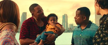 Movie still from “Bad Boys for Life” (2020), directed by Adil El Arbi – A man holding a baby in his arms while two other men look on; Medium shot, Over the shoulder angle