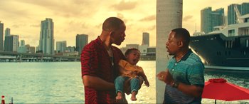 Movie still from “Bad Boys for Life” (2020), directed by Adil El Arbi – A man holding a baby in his arms while another man looks on; Medium shot, Over the shoulder angle
