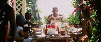 Movie still from “Bad Boys II” (2003), directed by Michael Bay – A group of people sitting at a table eating food; Medium shot, Low angle