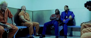 Movie still from “Bad Boys II” (2003), directed by Michael Bay – A group of men sitting next to each other on a bench; Wide shot, Low angle
