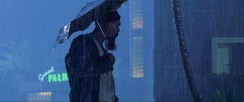 Movie still from “Bad Boys II” (2003), directed by Michael Bay – A man with a long beard holding an umbrella in the rain; Medium shot, Low angle