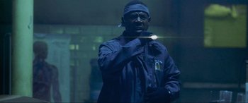 Movie still from “Bad Boys II” (2003), directed by Michael Bay – A man with a bandage on his head is holding a flashlight; Close Up shot, Low angle
