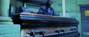 Movie still from “Bad Boys II” (2003), directed by Michael Bay – A man standing in front of an open casket; Medium shot, Low angle