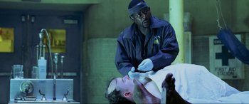 Movie still from “Bad Boys II” (2003), directed by Michael Bay – A police officer examines a man lying on the ground; Medium shot, High angle