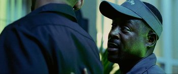 Movie still from “Bad Boys II” (2003), directed by Michael Bay – A man wearing a baseball cap talking to another man; Close Up shot, Over the shoulder angle