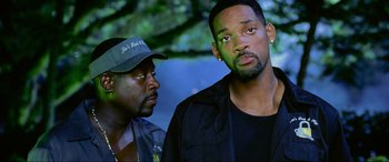 Movie still from “Bad Boys II” (2003), directed by Michael Bay – A man and a man standing next to each other in front of trees; Close Up shot, Over the shoulder angle
