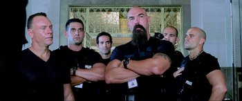 Movie still from “Bad Boys II” (2003), directed by Michael Bay – A group of men in police uniforms standing next to each other with their arms crossed; Medium shot, Low angle