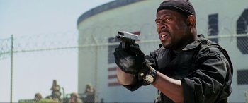 Movie still from “Bad Boys II” (2003), directed by Michael Bay – A man holding a gun and wearing black gloves; Close Up shot, Low angle