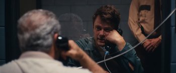 A man is talking on a phone in front of a mirror