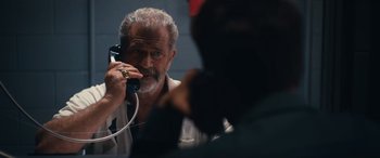 An older man talking on a phone while another man looks on