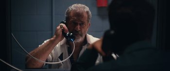 An older man talking on a phone in front of a mirror