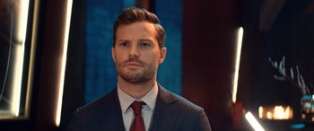 Movie still from “Barb and Star Go to Vista Del Mar” (2021), directed by Josh Greenbaum – A person wearing a suit and tie; Close Up shot, Over the shoulder angle