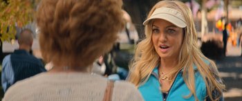 Movie still from “Barb and Star Go to Vista Del Mar” (2021), directed by Josh Greenbaum – A woman wearing a visor talking to another woman; Close Up shot, Over the shoulder angle