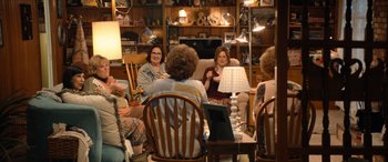 Movie still from “Barb and Star Go to Vista Del Mar” (2021), directed by Josh Greenbaum – A group of women sitting around a table; Wide shot, High angle