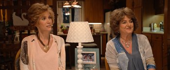 Movie still from “Barb and Star Go to Vista Del Mar” (2021), directed by Josh Greenbaum – Two women sitting in front of a lamp in a living room; Medium shot, Over the shoulder angle