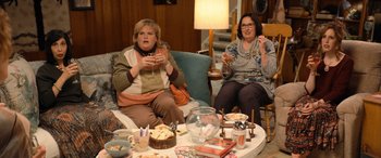 Movie still from “Barb and Star Go to Vista Del Mar” (2021), directed by Josh Greenbaum – Two women sitting in a living room eating cake; Medium shot, High angle