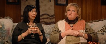 Movie still from “Barb and Star Go to Vista Del Mar” (2021), directed by Josh Greenbaum – Two women sitting on a couch with a glass of wine; Medium shot, High angle