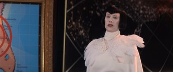 Movie still from “Barb and Star Go to Vista Del Mar” (2021), directed by Josh Greenbaum – A woman in a white dress standing in front of a mirror; Medium shot, Over the shoulder angle