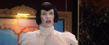 Movie still from “Barb and Star Go to Vista Del Mar” (2021), directed by Josh Greenbaum – A woman in a white dress with black hair and bangs; Close Up shot, Low angle