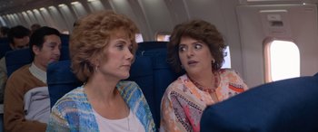 Movie still from “Barb and Star Go to Vista Del Mar” (2021), directed by Josh Greenbaum – A couple of women sitting next to each other on a plane; Close Up shot, Over the shoulder angle