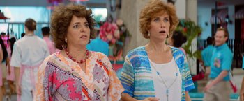 Movie still from “Barb and Star Go to Vista Del Mar” (2021), directed by Josh Greenbaum – A couple of women standing next to each other; Close Up shot, Over the shoulder angle