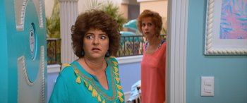 Movie still from “Barb and Star Go to Vista Del Mar” (2021), directed by Josh Greenbaum – Two women standing next to each other in front of a building; Close Up shot, Over the shoulder angle