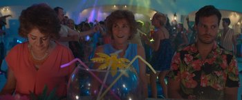 Movie still from “Barb and Star Go to Vista Del Mar” (2021), directed by Josh Greenbaum – A group of people in a room at a party; Medium shot, High angle